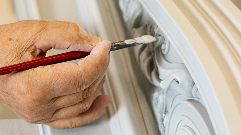 man paints carving on furniture