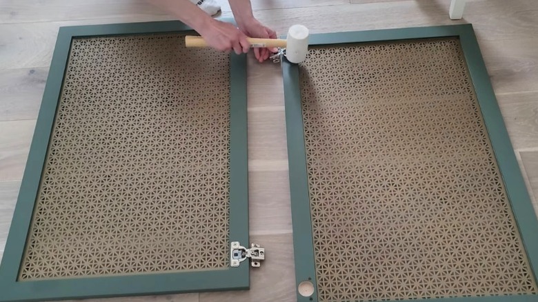 Person assembling cabinet door fronts with metal mesh panel