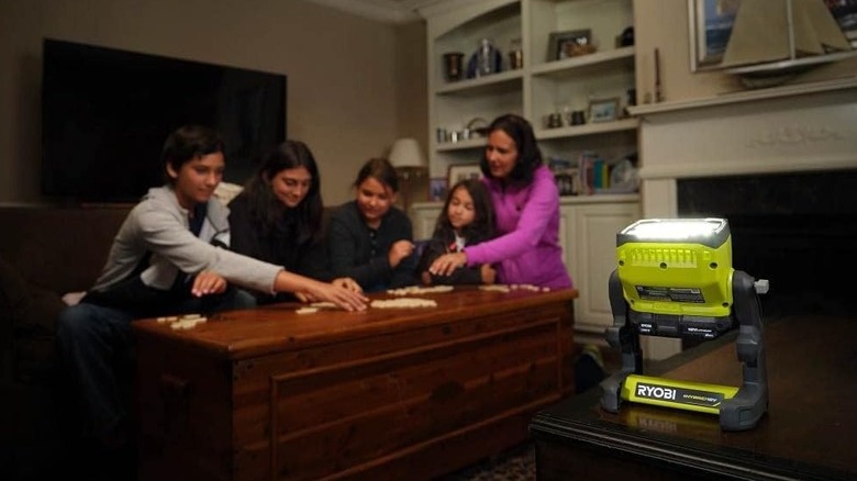 People playing a game during a power outage with light from a Ryobi floodlight