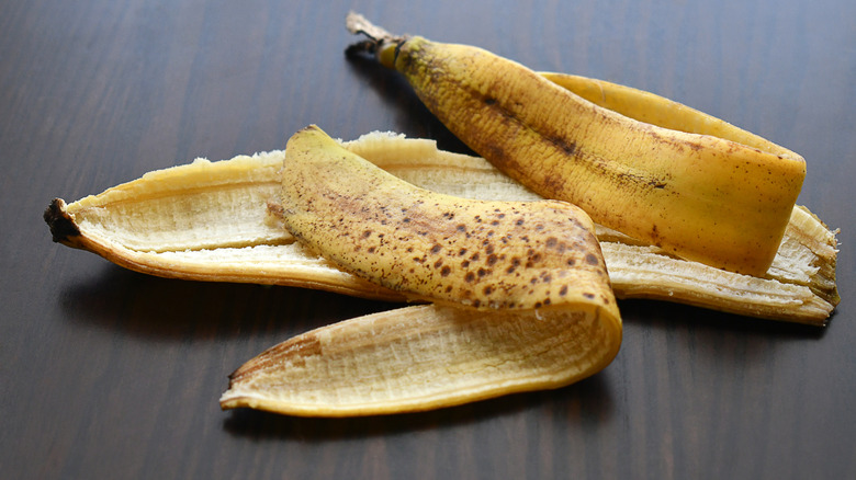 A brown banana peel on a wood table.