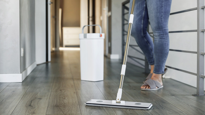 A woman mopping her floors with a flat mop and bucket.