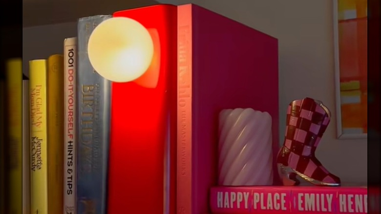 A plastic IKEA magazine rack, painted red and fitted with a bulb and wiring, becomes a bookshelf lamp.