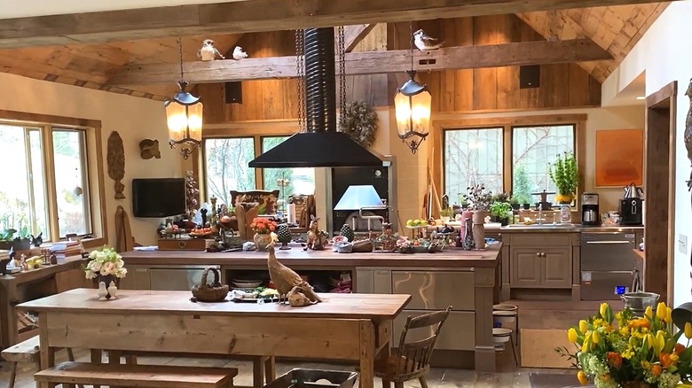 Rachael Ray's farmhouse kitchen with wood and stainless steels cabinets, a butcherblock island, and black exposed pipe range hood.