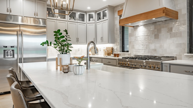 Interior modern farmhouse kitchen and dining room with white countertops bar stools large dining table stainless appliances and view to living room