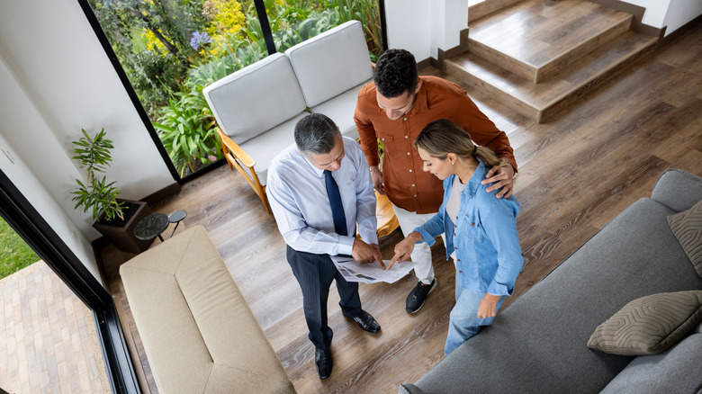 Top view of a real estate agent showing customers a house blueprint