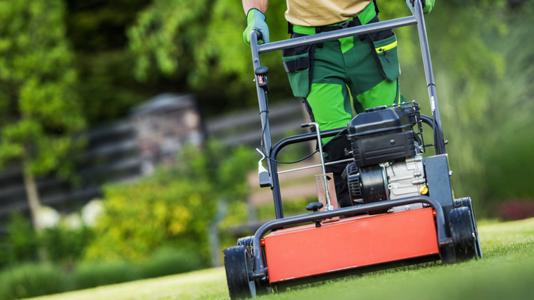 A man using gas powered aerating machine to aerate a lawn