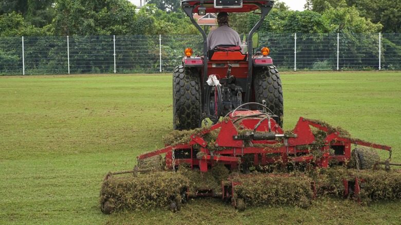 Tractor aerating a sports field with turf equipment