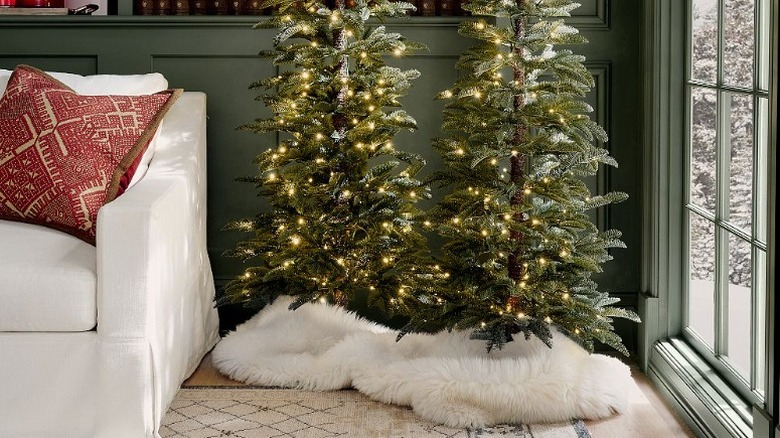 Two Christmas trees styled with furry white blanket over base