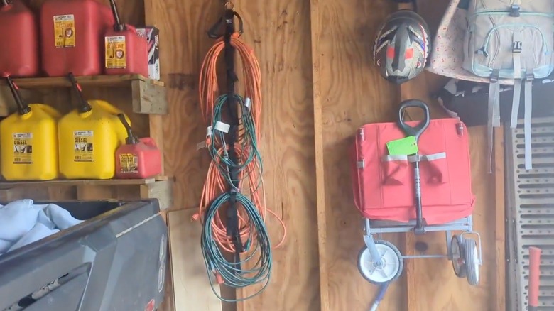 A wood wall in garage with extension cord organizer.