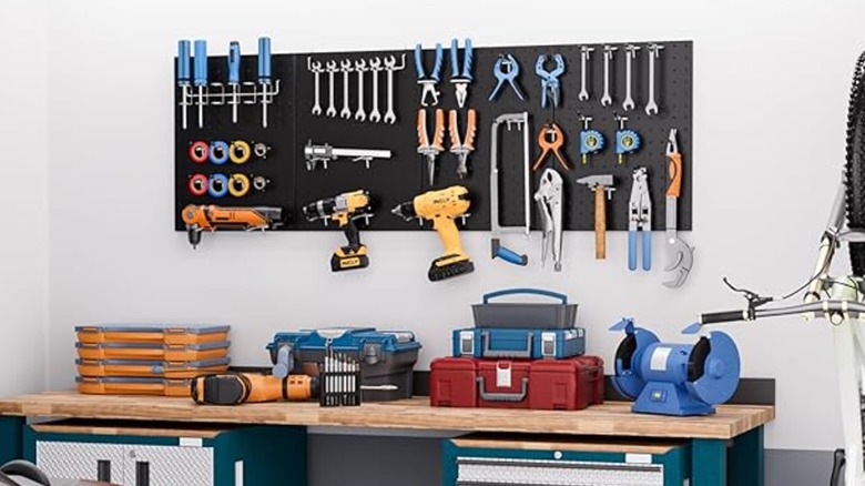 Black pegboard on wall holding garage tools.