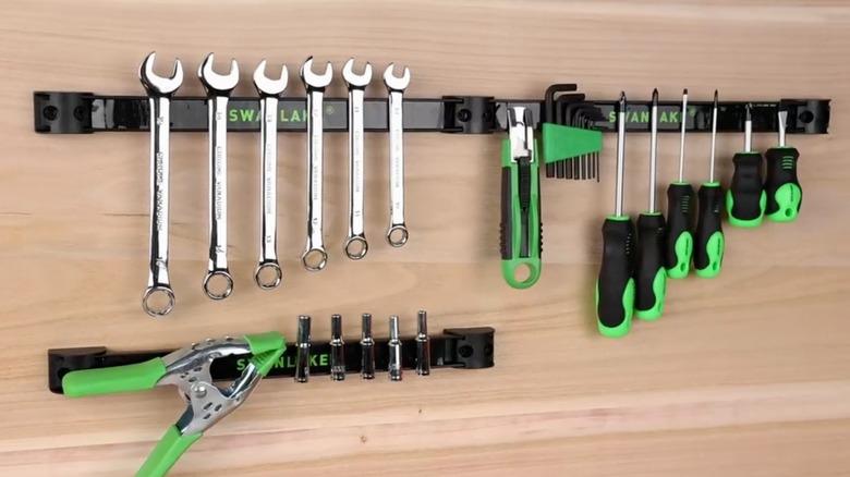 Black magnetic strips holding tools on wall.