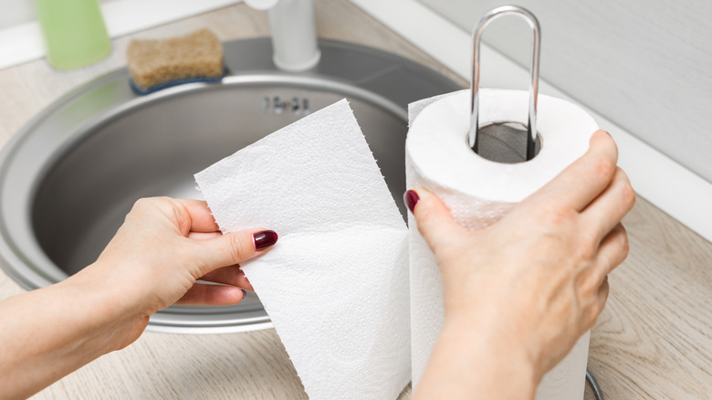 a hand putting a roll of paper towels on paper towel holder