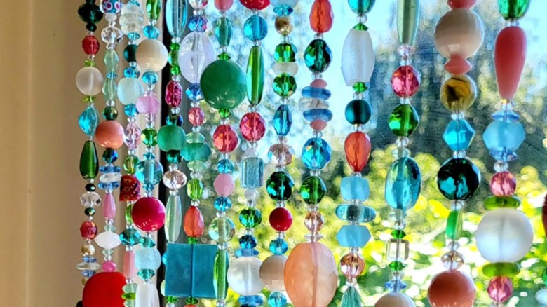 Colorful glass beaded curtain over window glass