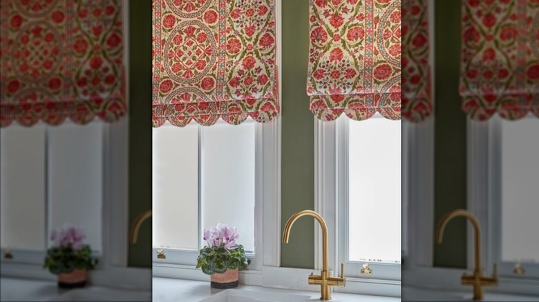Patterned red and green roman shades over kitchen sink