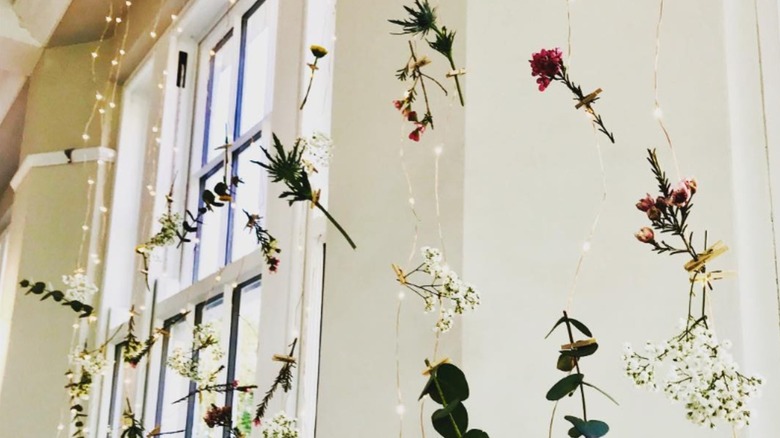 Artificial flowers strung on fairy lights over window