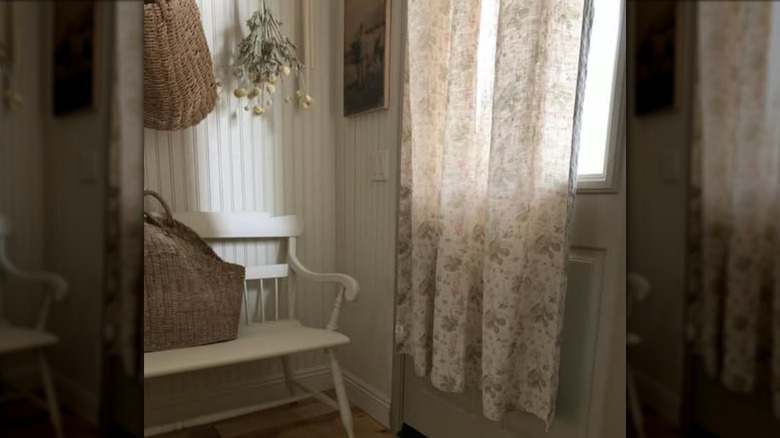 Patterned floral tablecloth hung over window on door
