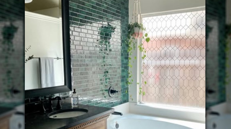 Patterned window film over bathtub near green tile wall