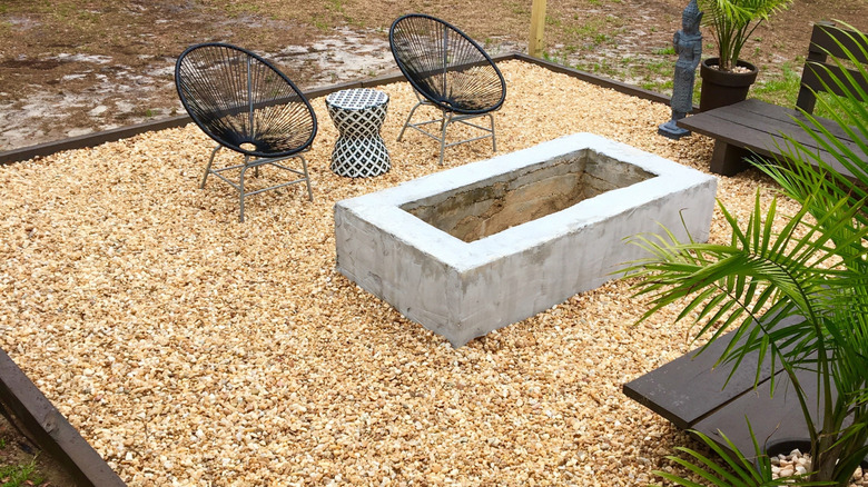 A pea gravel patio sits below chairs, benches, and a fire pit.