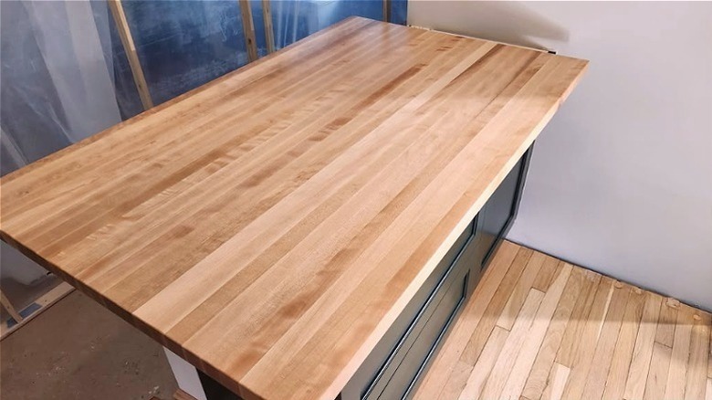 Red birch butcher block countertop on an island during kitchen renovation.