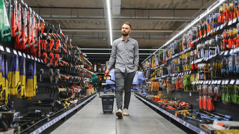 A man with a shopping cart walking through a hardware store