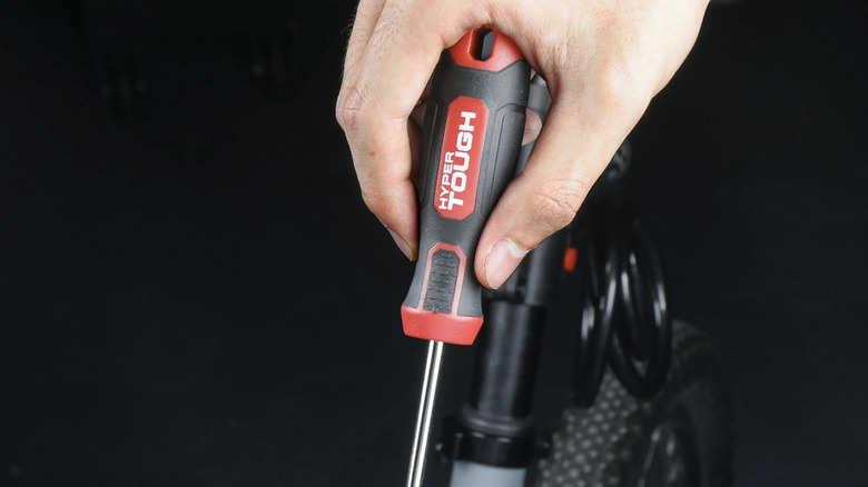 A person using a red and black Hyper Tough brand screwdriver