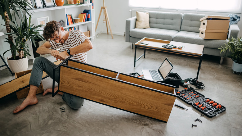 A man putting together furniture and using a screwdriver kit