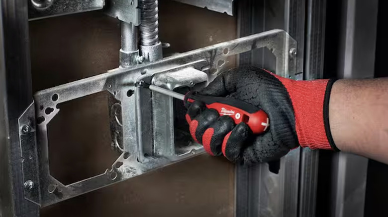 A man using a Milwaukee screwdriver to fasten a screw