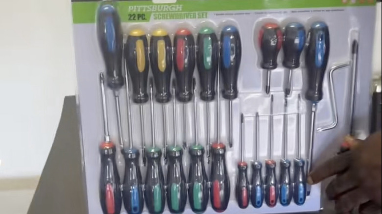A man opening a 22 piece screwdriver set