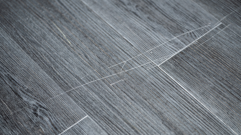 Broken vinyl flooring with a visible scratch.