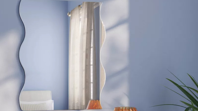 A squiggle mirror on a light blue wall.