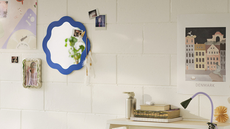The PRUNKHALLON mirror from IKEA on white cinderblock wall with photos and art work