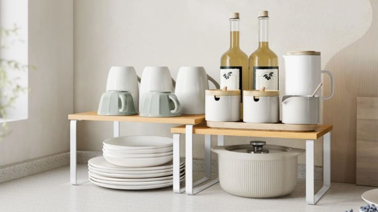 Two shelves holding dishes sitting on a counter