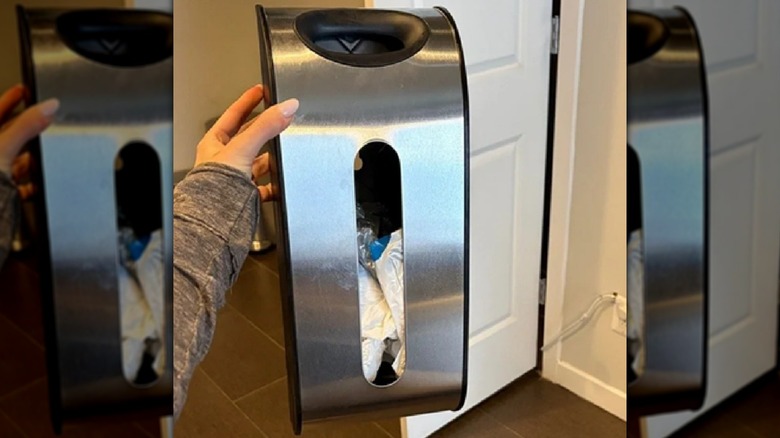 Hand holding stainless steel bag dispenser