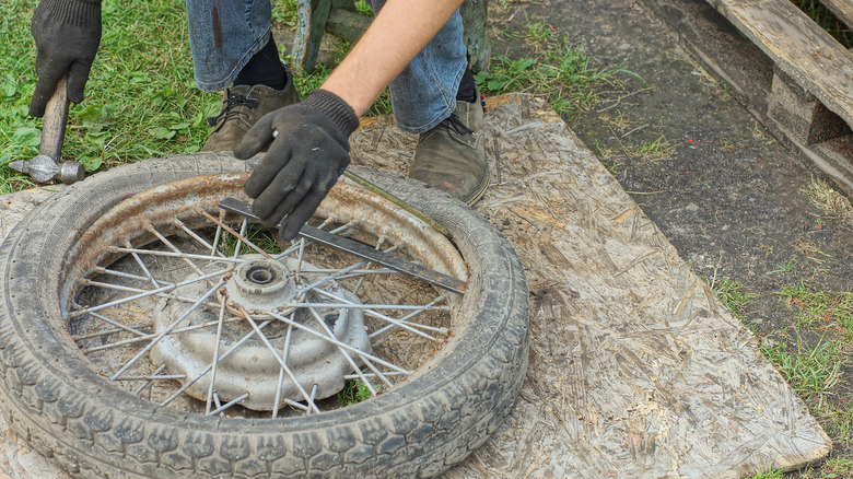 removing the rubber of an old bicycle tire in a yard