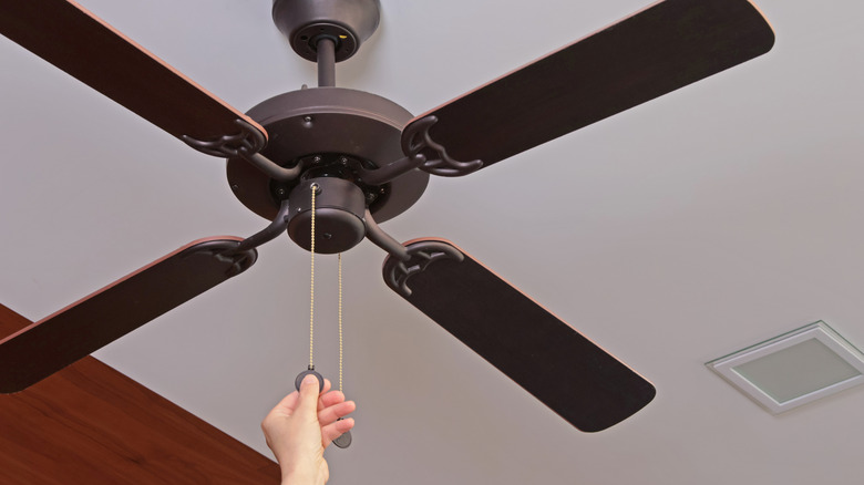 woman pulling the cord on a ceiling fan