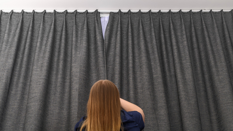 woman closing blackout drapes