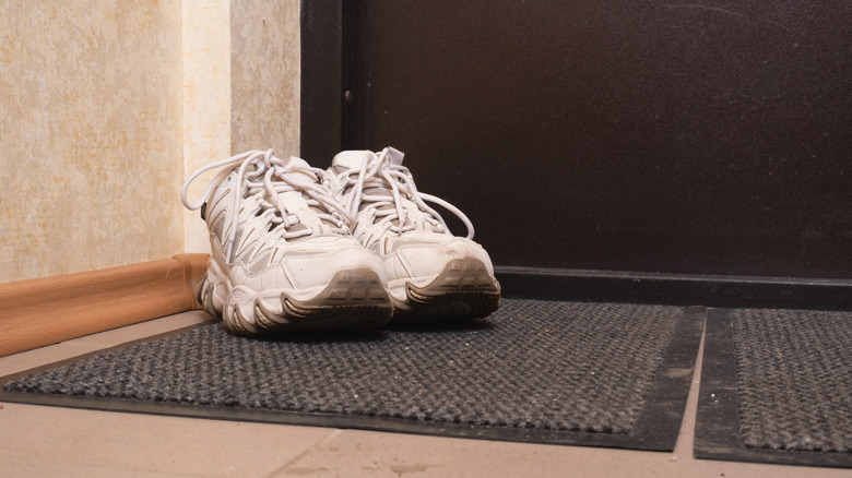 Dirty sneaker placed over a doormat outside a home