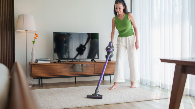 Woman vacuuming a beige rug in her apartment