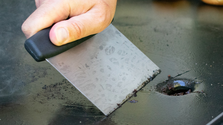 Using steel scraping tool to clean a griddle