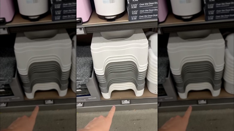 Hand pointing at Aldi's bathroom footstools on store shelf