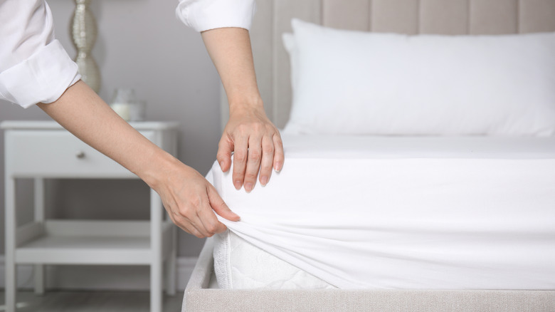 A person makes a bed with new bedsheets