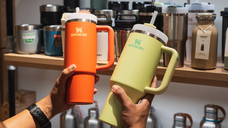 Person holding two stanley brand cups in a store