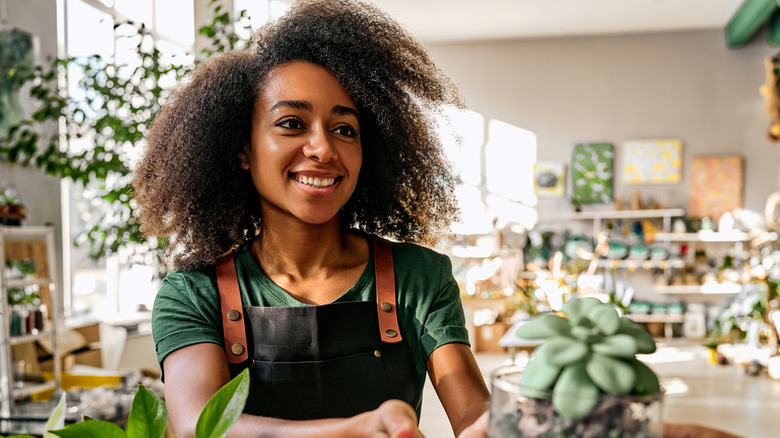 Woman surrounded by plants being handed a small succulent