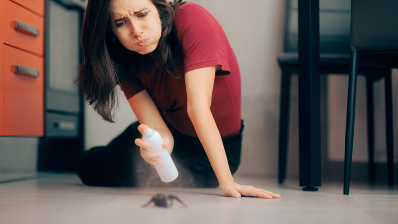 Woman in red shirt spraying spider with an aerosol can