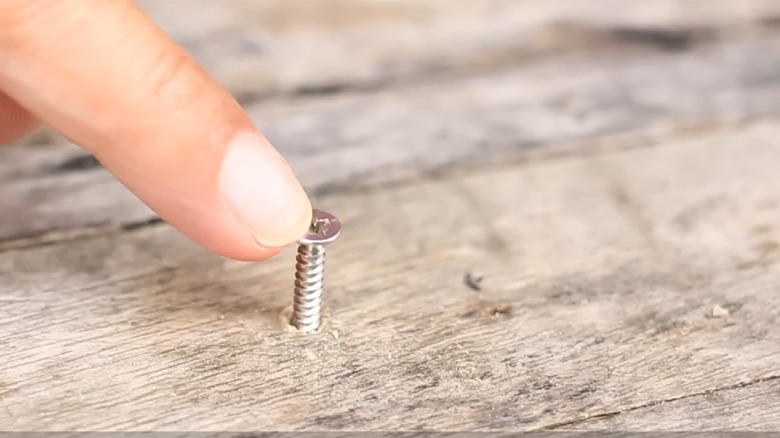 Finger tapping a loose screw in a piece of wood