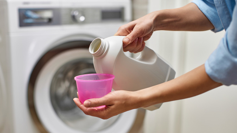 Hands pouring bleach in a pink plastic cup