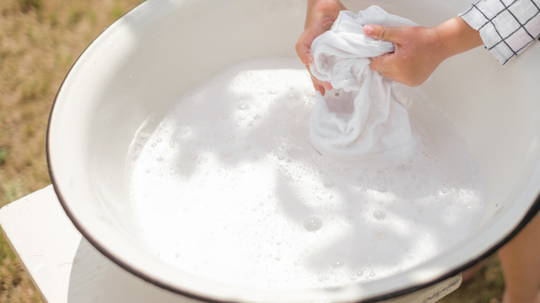 Hand washing white garments in a large basin