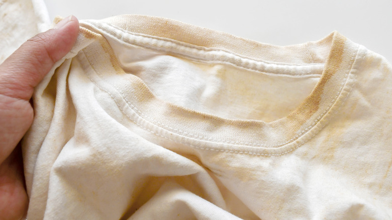 Hand holding a stained and yellowed white shirt