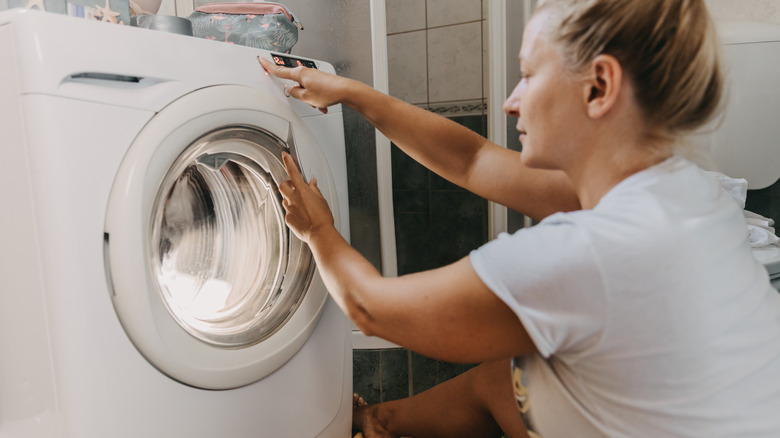 Woman choosing a setting on a washing machine