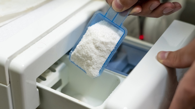 Hand adding detergent powder in washing machine slot